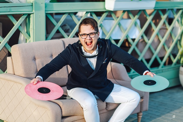 Hipster houdt vinylplaten zittend op de bank in een koffie