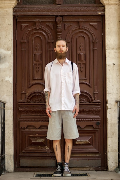 Hipster in wit overhemd poseren voor een deur buiten in de stad. Stijl en diversiteit