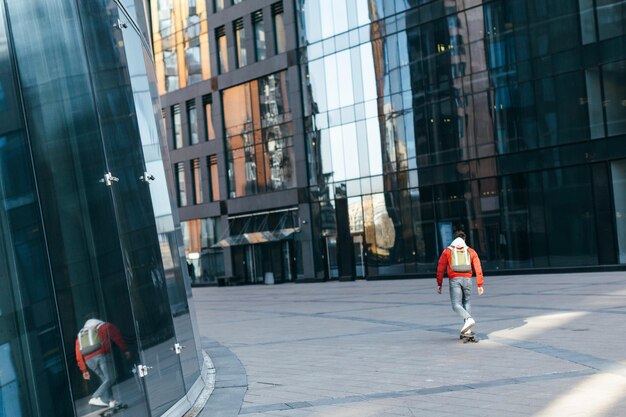 hipster in jacket with green backpack riding on longboard Urban and street photo Healthy lifestyle