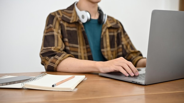 Hipster jonge Aziatische man in flanellen hemd aan zijn bureau met behulp van notebook laptop