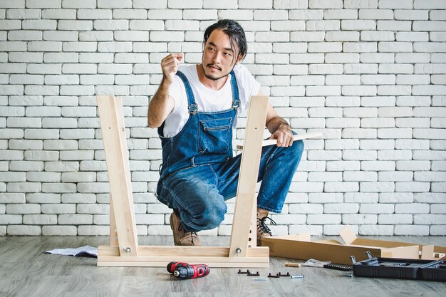 Hipster jonge man aan het werk als klusjesman, houten tafel monteren met apparatuur,