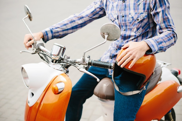 Hipster jongeman in helm rijdt op gele retro scooter in de stad