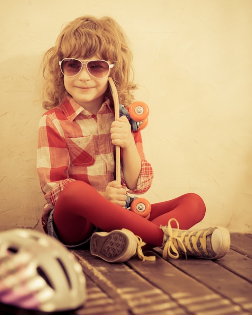 Hipster kid holding skateboard in hands