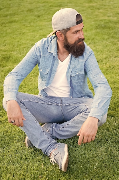 Hipster lifestyle Cool hipster with beard wear stylish baseball cap Brutal handsome hipster man resting on summer day Bearded man trendy hipster style Guy modern outfit Casual and comfortable