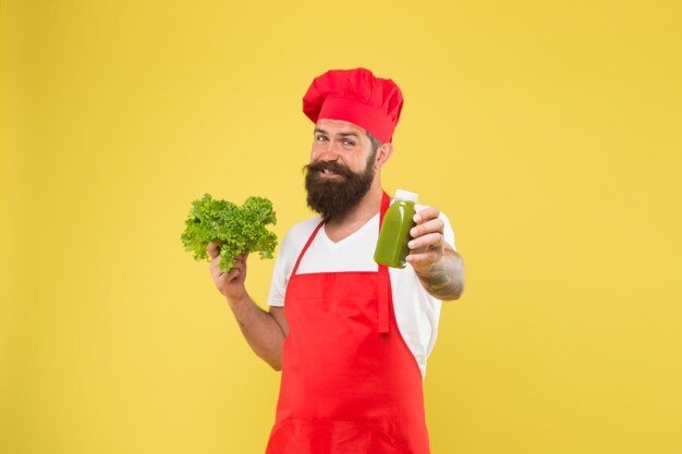 Hipster maakt smoothie cocktail gezond eten en dieet concept kok houd verse en gemengde salade smoothie rauw gezond voedsel concept biologische eco veganistische producten bebaarde man chef-kok in schort en hoed