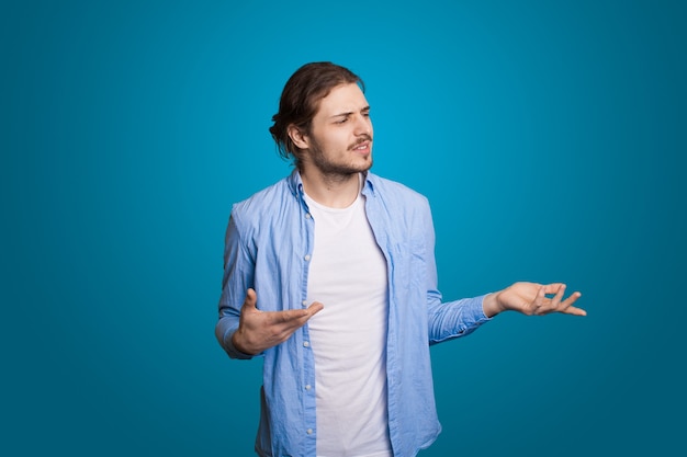 Hipster man on blue wall with long hair posing pensive for fashion lifestyle design handsome man blu.