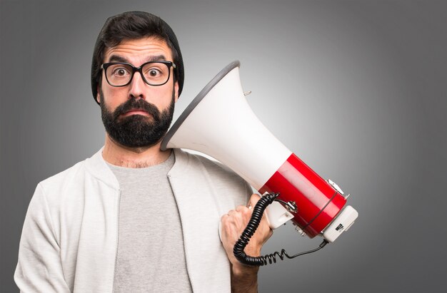 Hipster man holding a megaphone on grey background