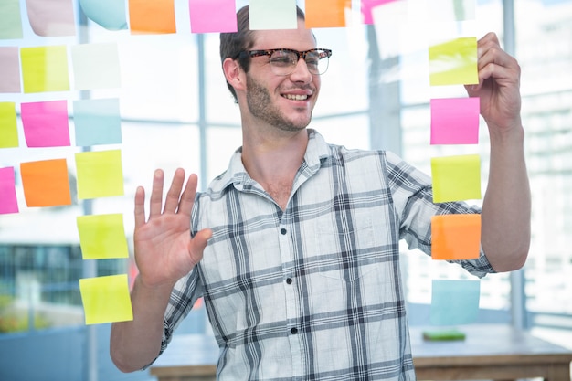 Hipster man looking at post-it in office