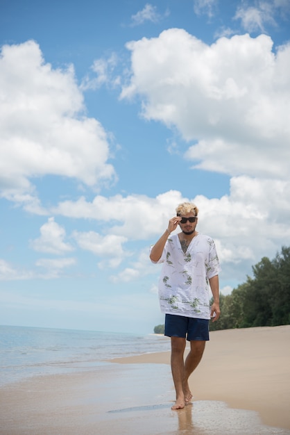 Hipster man lopen op de achtergrond van mooi strand met witte wolk en mooie lucht