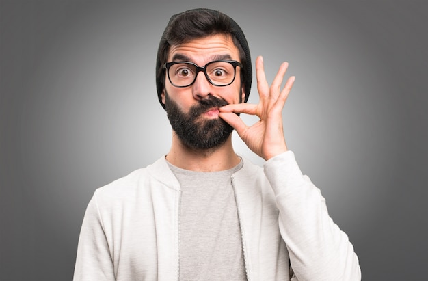 Hipster man making silence gesture on grey background