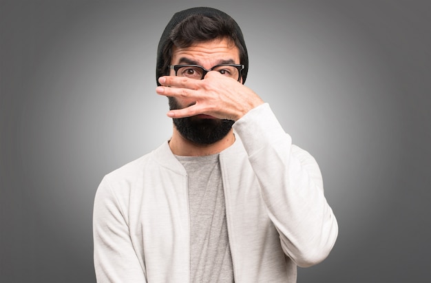 Hipster man making smelling bad gesture on grey background