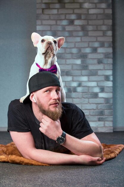 Hipster man met zijn aardige Franse Bulldog dogdressed in vlinderdas tegen bakstenen muur op achtergrond Huisdieren houden van concept