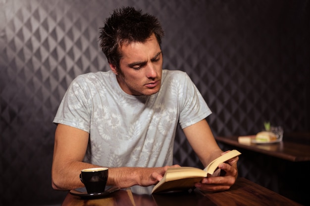 Photo hipster man reading while drinking coffee