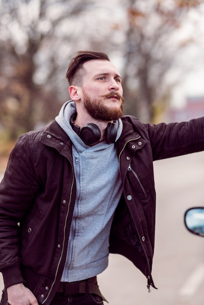 Hipster man standing next to a car