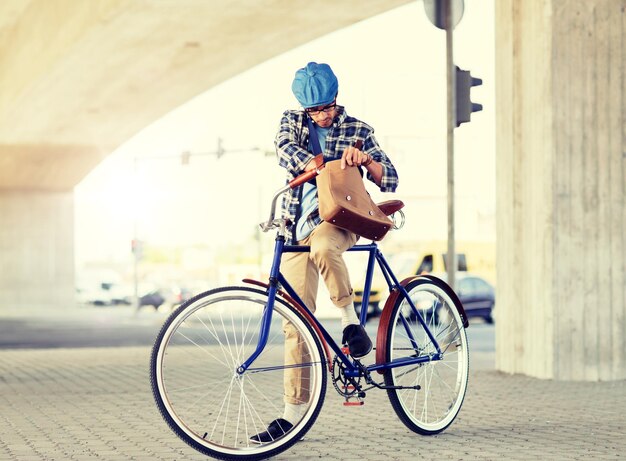 Foto uomo hipster con una borsa sulla spalla su una bicicletta a marcia fissa