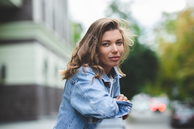 Hipster meisje in schone witte t-shirt en jeans poseren tegen de achtergrond van gebouwen