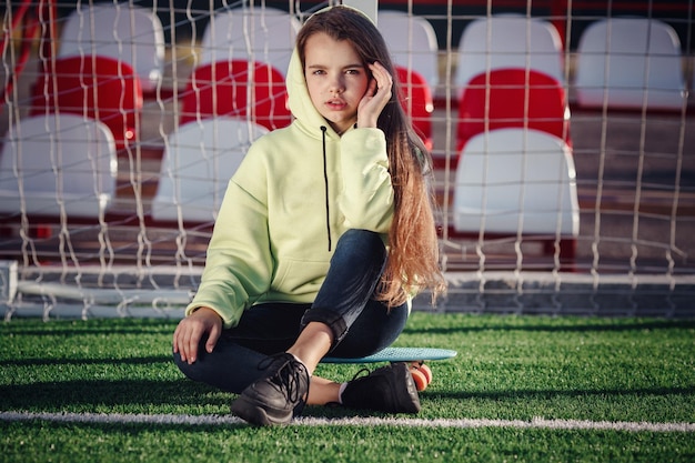 Hipster meisje met skateboard buitenshuis Modern meisje met een skateboard dat op een stadion loopt Rust van studie Outdoors Lifestyle