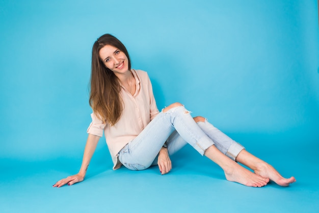 Hipster meisje, zittend op de vloer tegen blauw