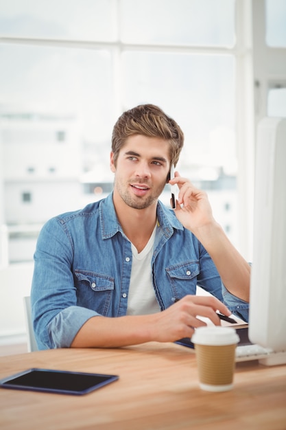 Hipster met behulp van mobiele telefoon tijdens de vergadering op het bureau