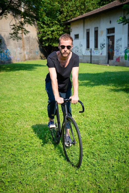 ヒップスター現代的なスタイリッシュなブロンドの男と自転車