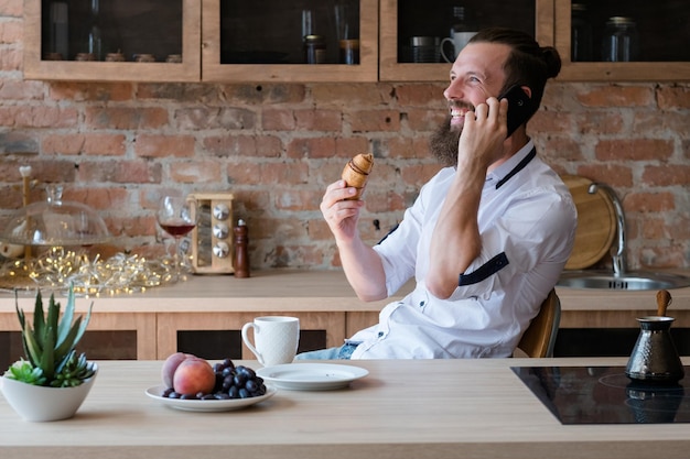 Hipster morning Fruit and pastry snack for breakfast Cup of drink Good news on phone Excited man talking on mobile