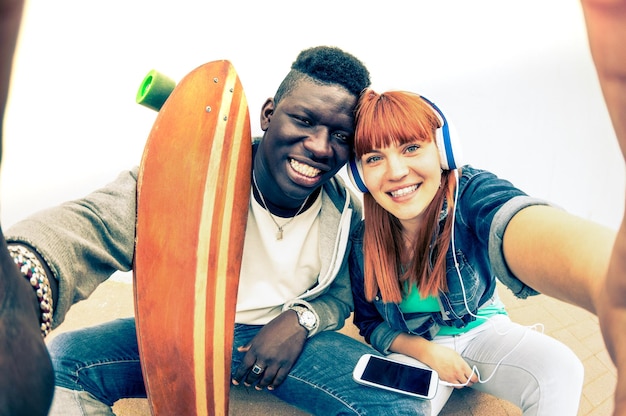 Hipster multiracial couple in love taking selfie on white background