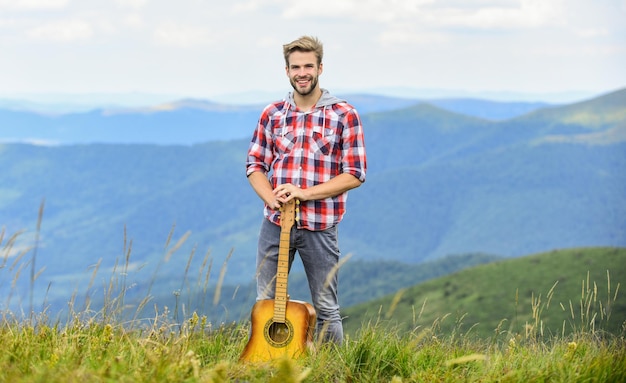 Hipster muzikant Inspirerende omgeving Zomer muziekfestival buiten Muziek spelen Man muzikant met gitaar op topberg Geïnspireerde muzikant Stilte van bergen en geluid van gitaarsnaren