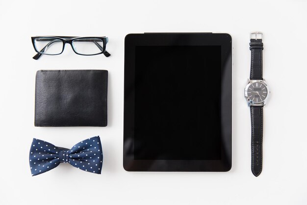 Photo hipster personal stuff and objects concept - tablet pc computer, wallet, eyeglasses, bowtie and wristwatch on table