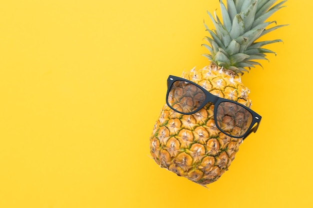 Photo hipster pineapple with sunglasses against a yellow background