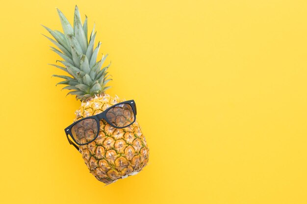 Hipster pineapple with sunglasses against a yellow background