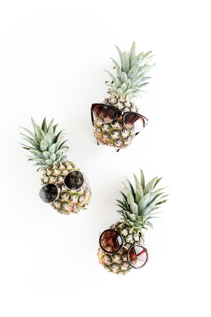 Hipster pineapples in glasses on white background flat lay top view