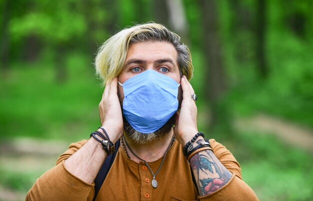 Hipster protecting from air contamination or coronavirus Virus infection Man enjoy nature wearing face mask Avoid infection Stop infection Slowly emerge from lockdown restrictions Walk in park