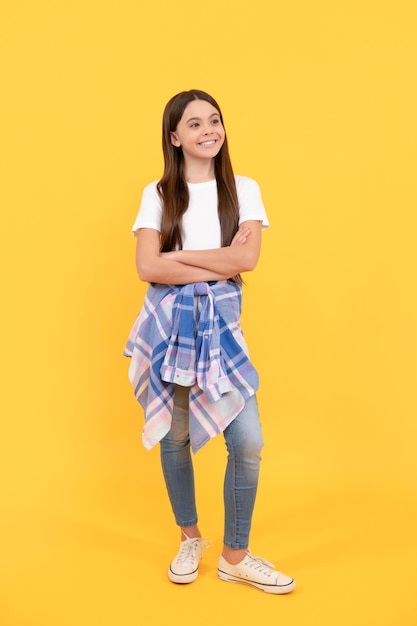 Hipster smiling child in casual clothes full length on yellow background