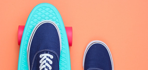 Hipster sneakers op skateboard bovenaanzicht op koraal achtergrond. Minimalisme mode-concept