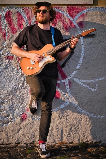 Hipster street musician in black playing electric guitar in street on sunset Lisbon Portugal