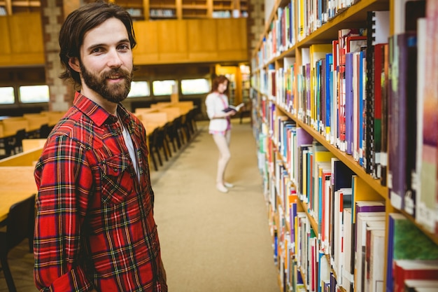 Foto studente dei pantaloni a vita bassa che seleziona un libro in biblioteca