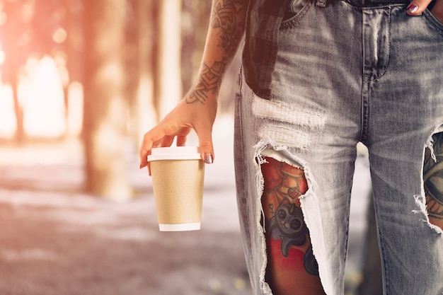 hipster tattooed girl in park with  coffee