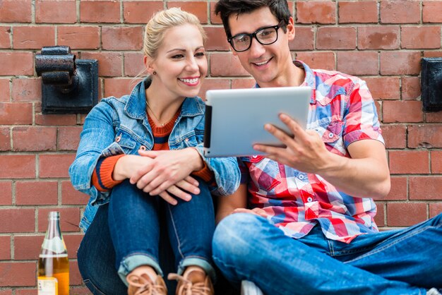 Hipster toeristen die vakantie in berlijn met stootkussencomputer plannen