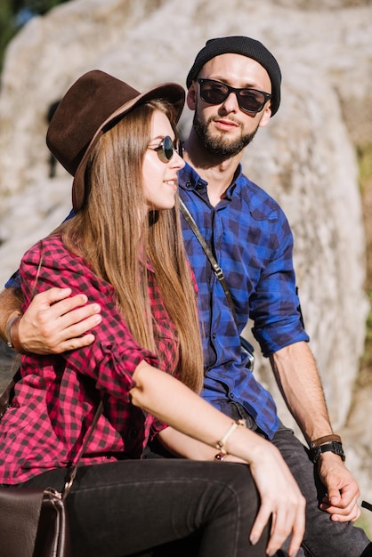 A hipster traveler couple sitting together on the rocks at the mountains