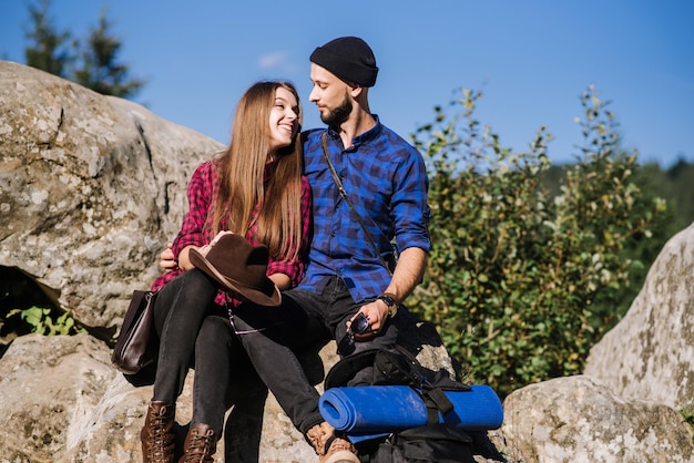 A hipster traveler couple sitting together on the rocks at the mountains