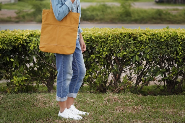 Hipster vrouw met gele bolsazak op groen gras