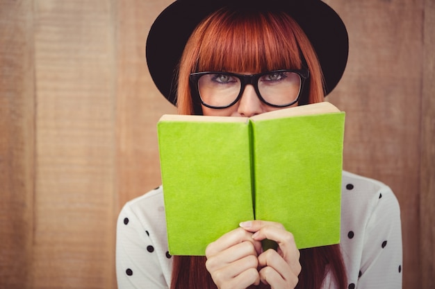 Hipster woman behind a green book