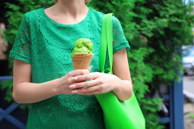 公園でアイスクリームを持っている緑のレースのドレスを着た流行に敏感な女性