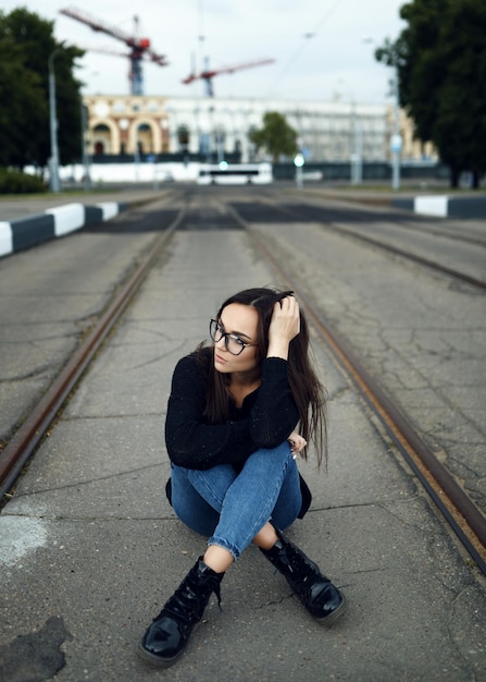 Hipster woman sitting on the road in the summer in the city The concept of lifestyle and fashion