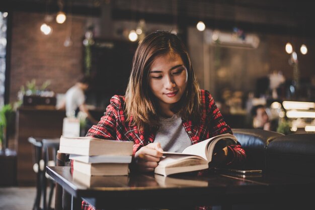 写真 カフェで本を読むのを楽しんでいるヒップスターのティーンエイジャーの女性 ヴィンテージフィルター