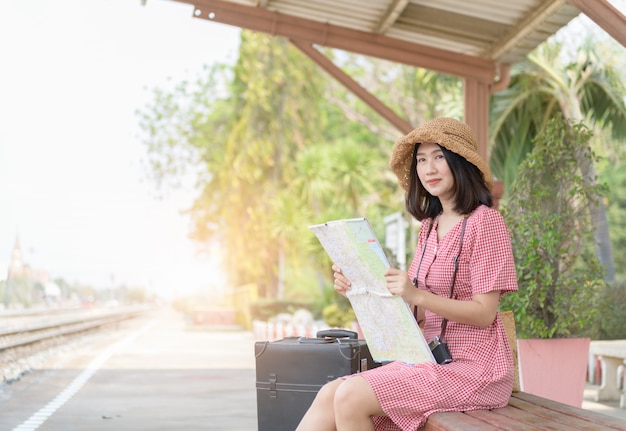 流行に敏感な女性が地図を見て電車を待っています。