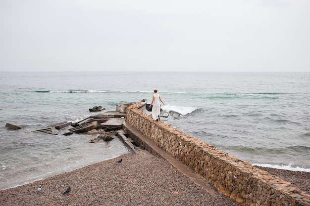 Hipster woman wearing dress near sea in autumn