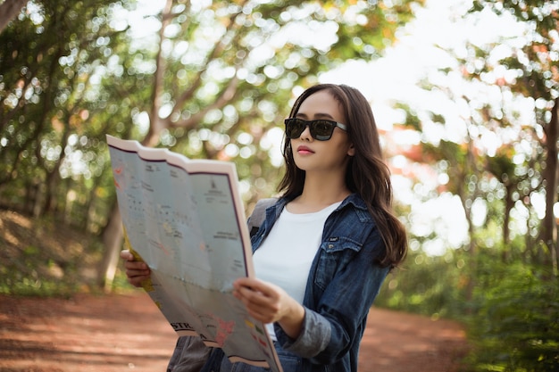 バックパックと流行に敏感な女性はタイのジャングルの中で夏に旅行しています。