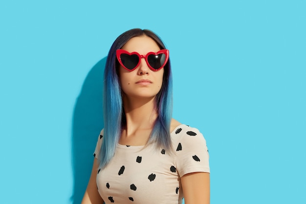 Hipster woman with blue hair wearing sunglasses serious 