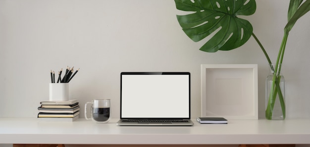 Luogo di lavoro hipster con computer portatile schermo vuoto con telaio e forniture per ufficio